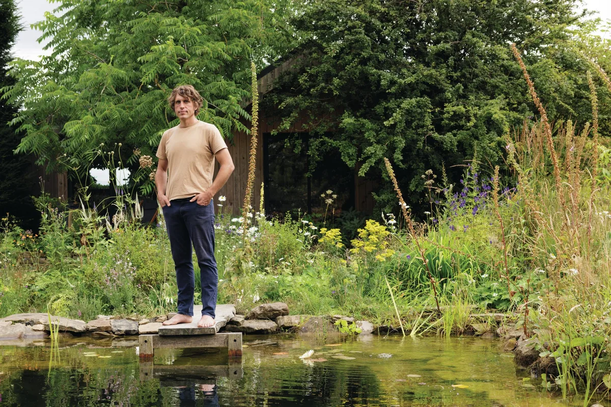 Will Tomson at his natural swimming pool Man stood in garden by swimming pond