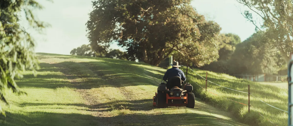 Man on ride on mower in field Man on ride on mower in field