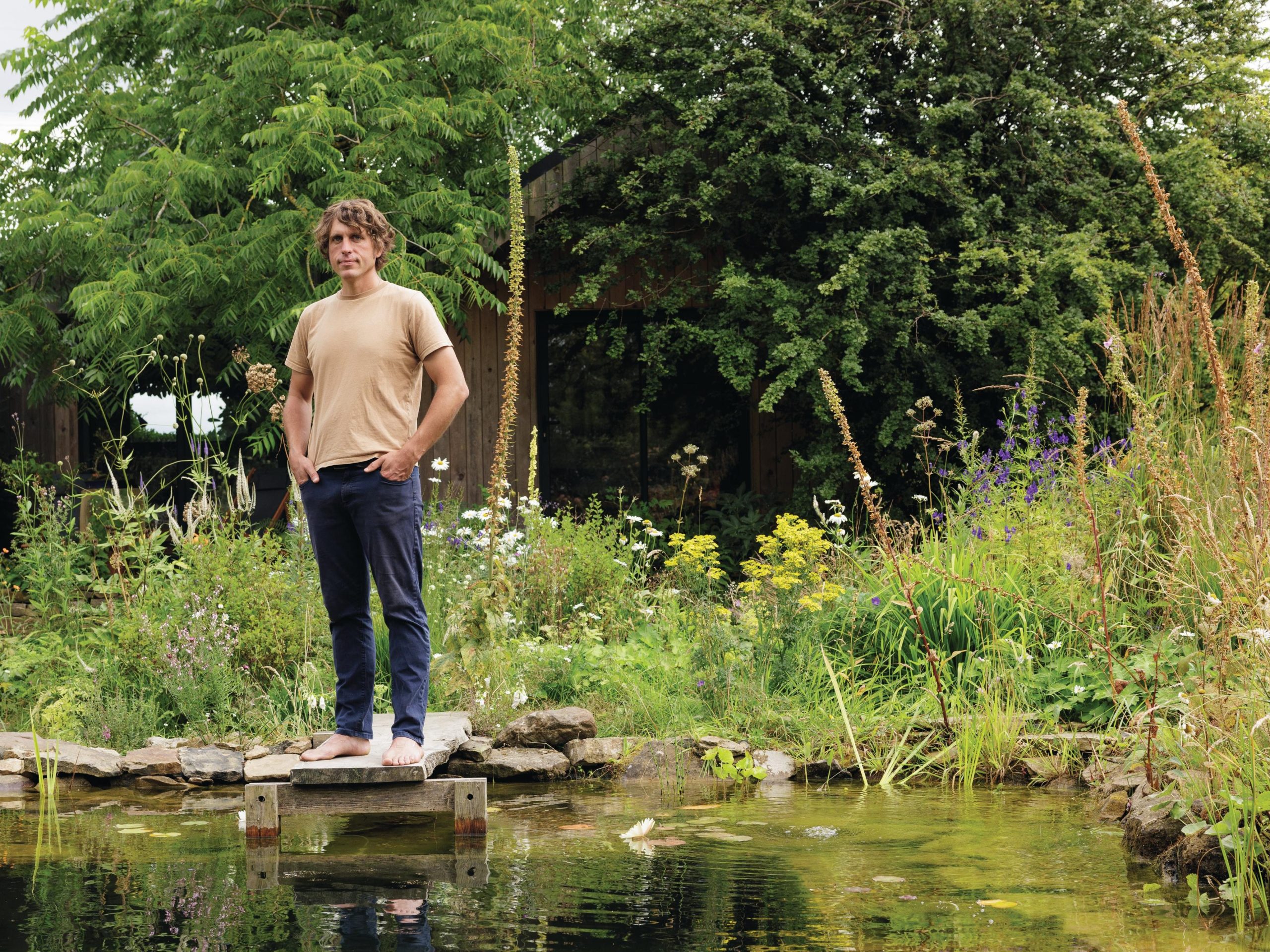 Man stood in garden by swimming pond